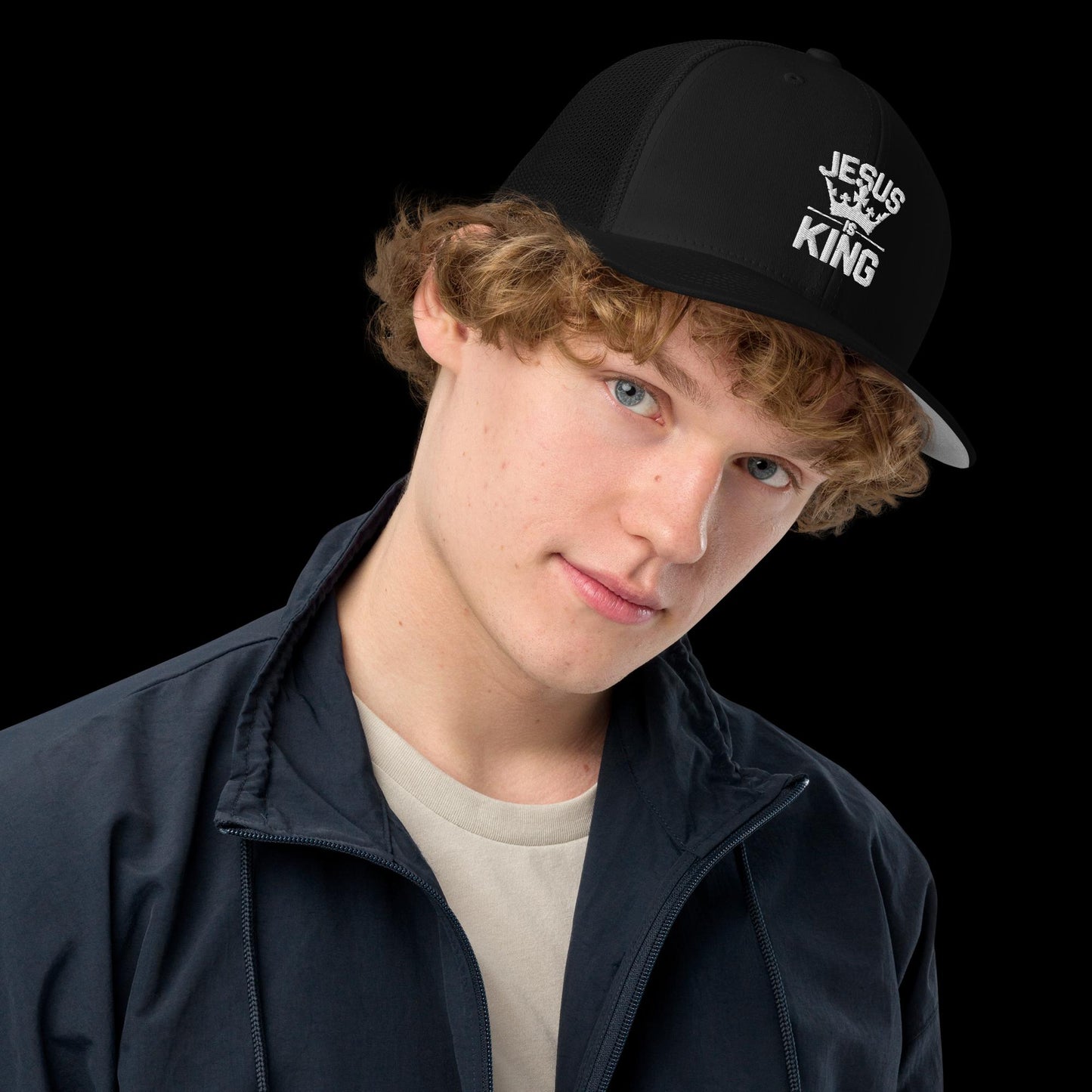 Black Christian Trucker Cap – “Jesus Is King” embroidered hat with crown graphic, faith-based streetwear accessory modeled by young man in casual outfit, perfect for bold Christian fashion.