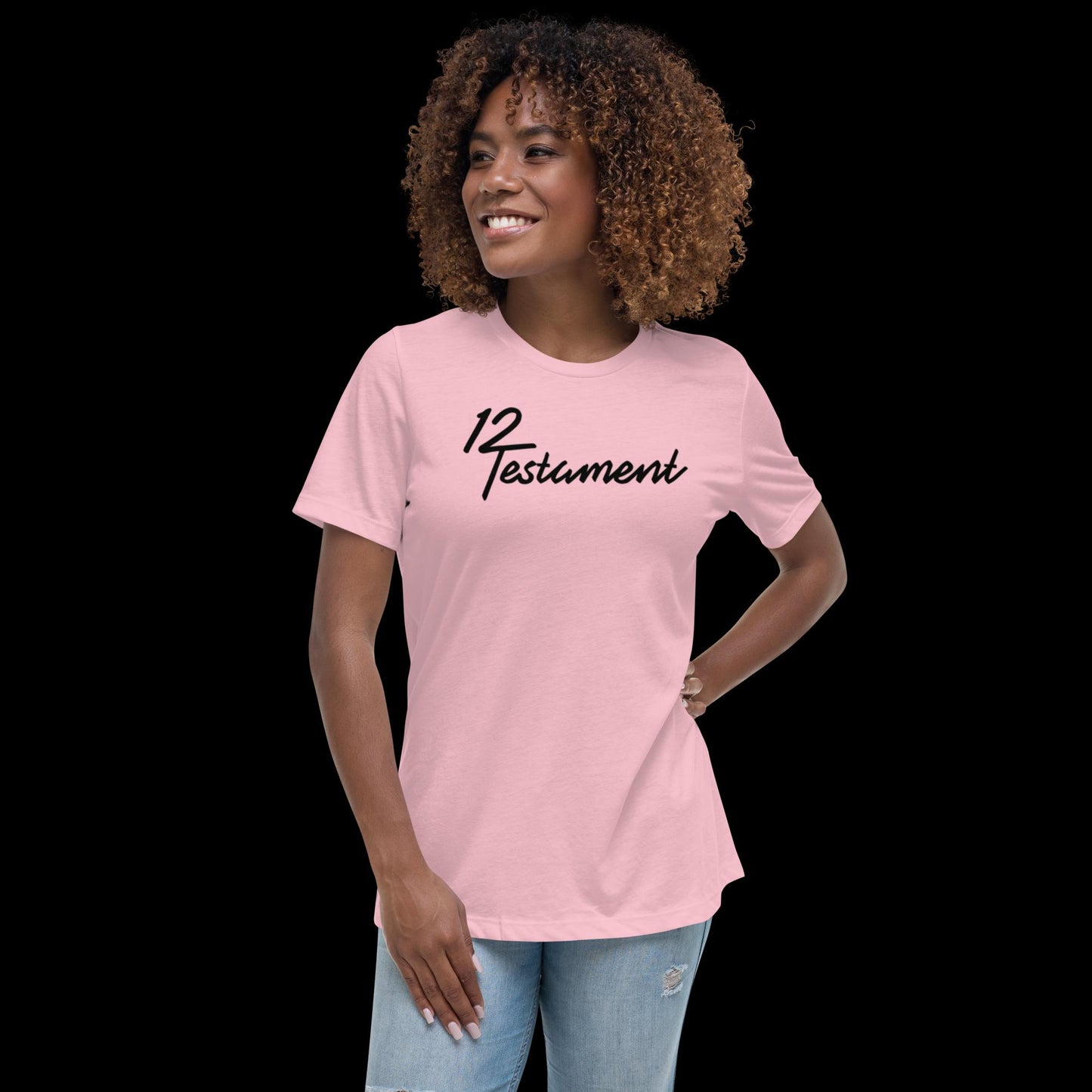 Pink Christian Women’s T-Shirt – Relaxed-fit tee featuring bold black “12 Testament” script logo, faith-inspired apparel modeled by smiling woman in distressed jeans.