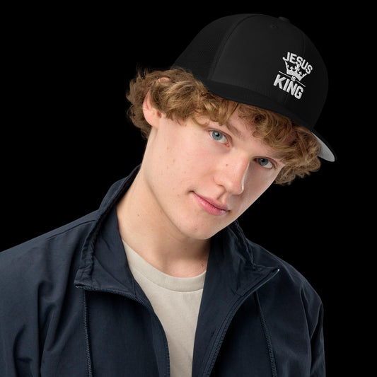 Black Christian Trucker Cap – “Jesus Is King” embroidered hat with crown graphic, faith-based streetwear accessory modeled by young man in casual outfit, perfect for bold Christian fashion.