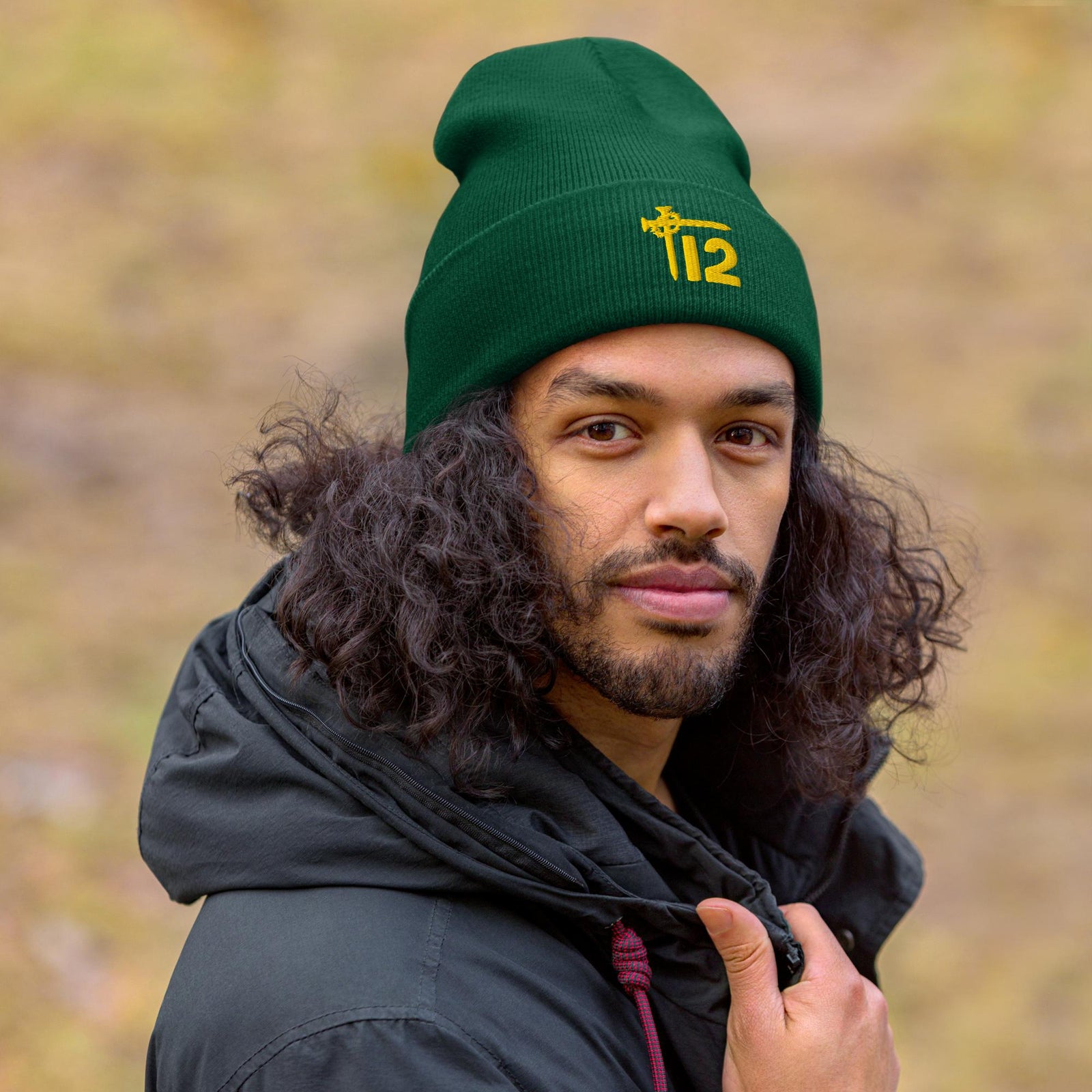 Man wearing a spruce green T12 Christian beanie with cross sword logo, modeling faith-based winter hat outdoors.