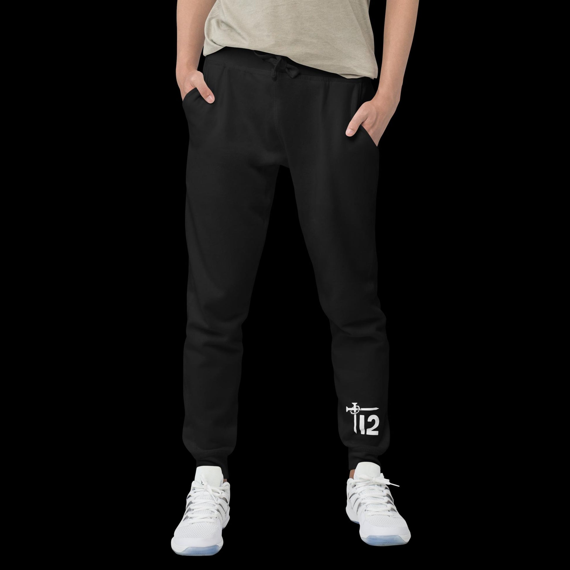 Black Christian Sweatpants – Unisex fleece joggers with white embroidered “12T” logo featuring cross nail and crown of thorns design on leg, faith-inspired streetwear modeled with sneakers.